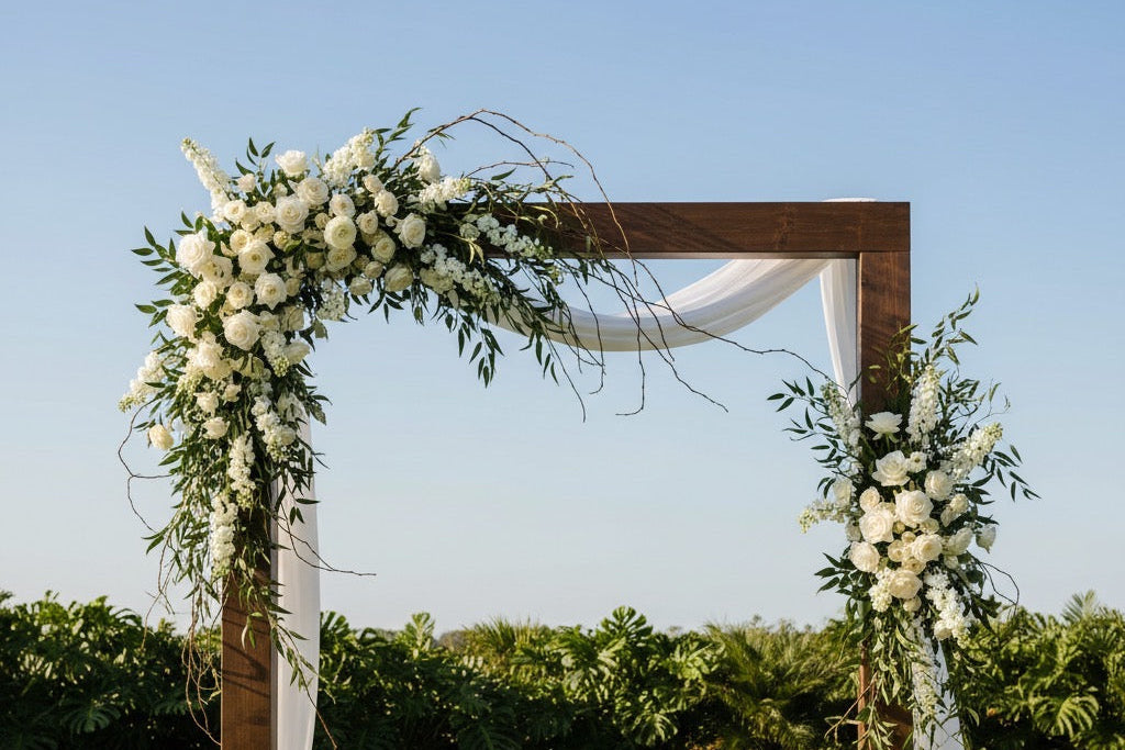 Decorative wedding arch with floral arrangements on a grassy field.